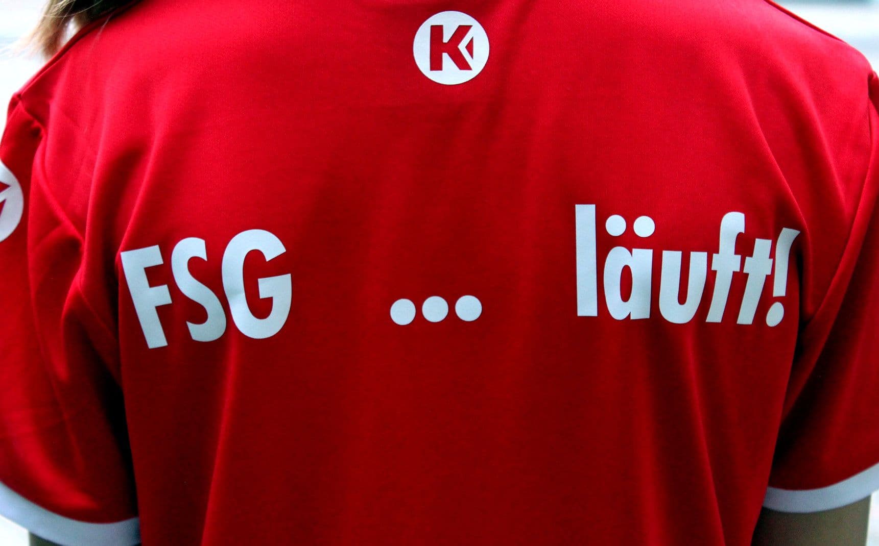 Back of a red shirt with "FSG ... läuft!" in white text and a white circular K logo.