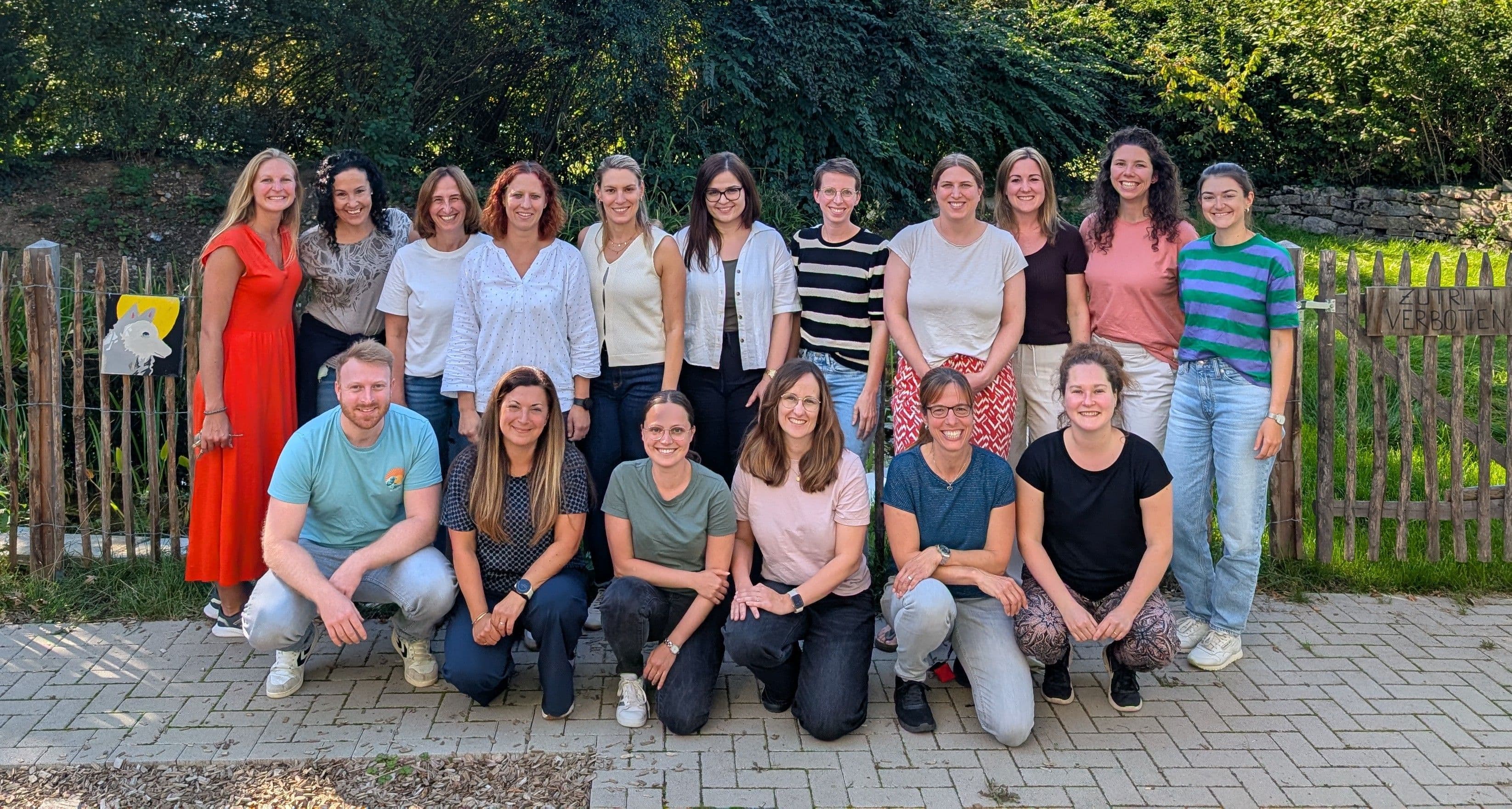 a group of people are posing for a picture in front of a wooden fence .