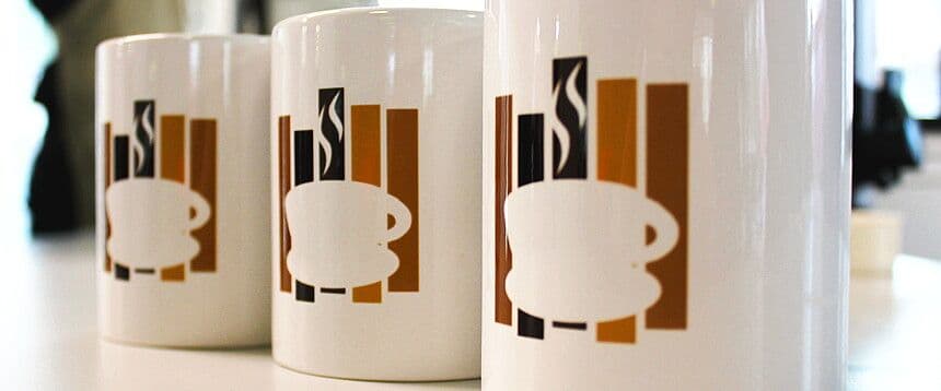 three coffee mugs with coffee cups on them are sitting on a table .