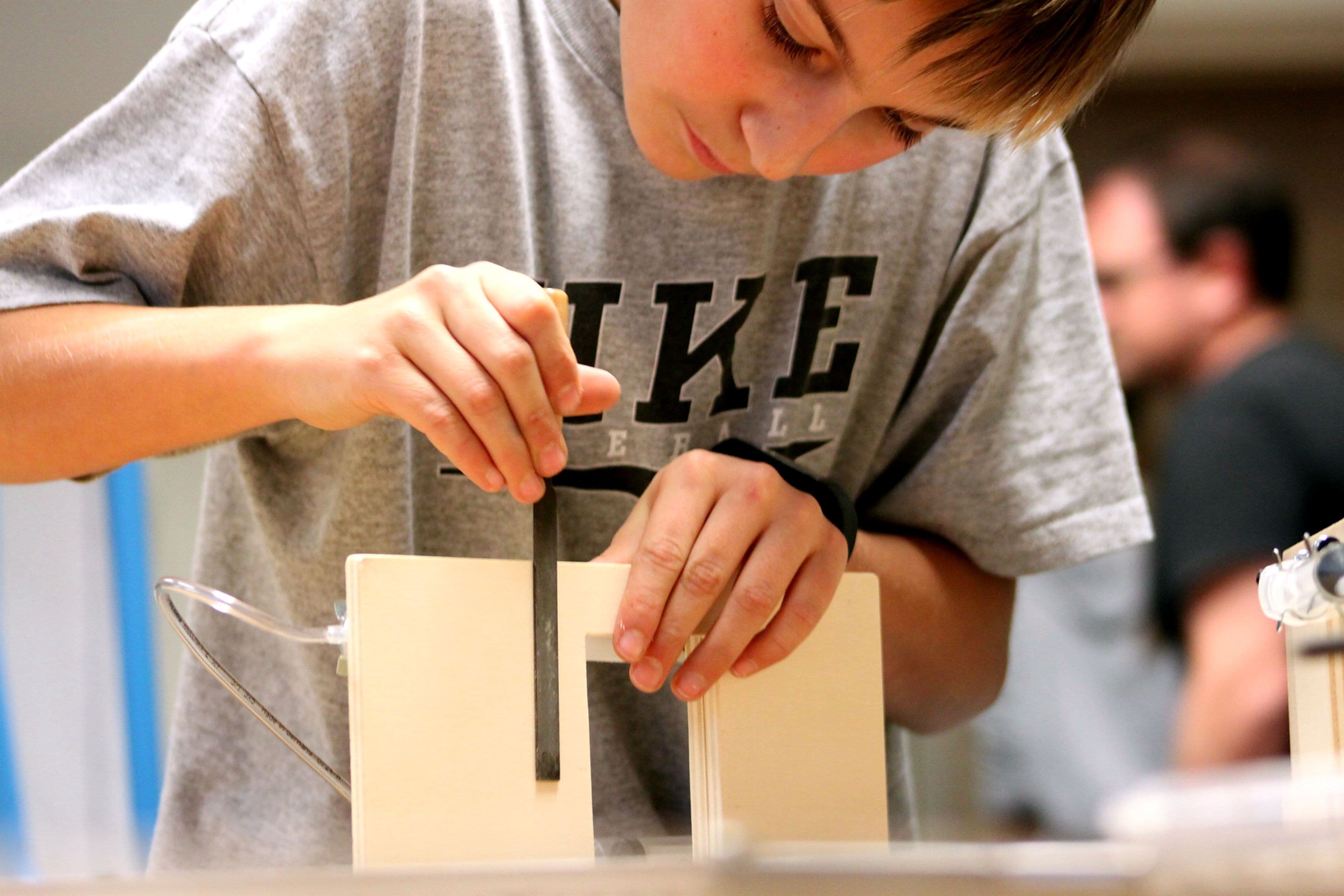 a young boy is measuring a piece of wood with a tape measure .