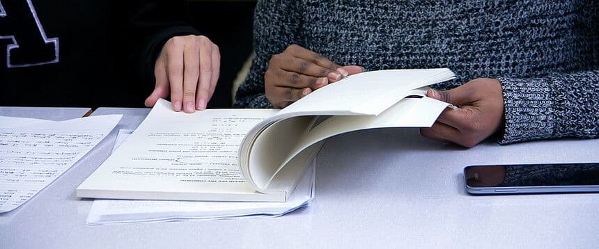 zwei Personen blättern in einem Heft