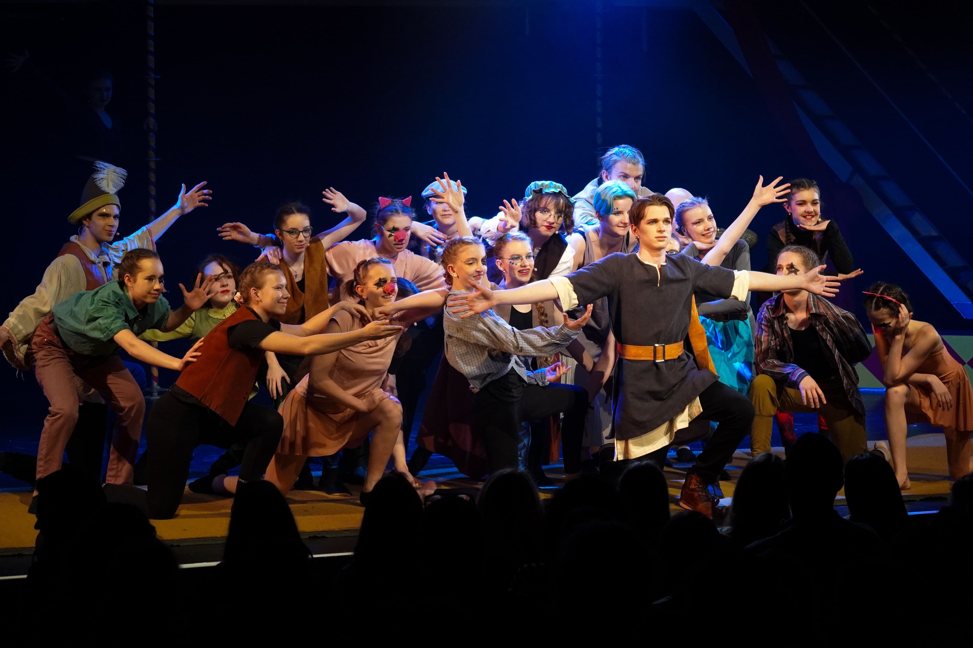 a group of young people are dancing on a stage in front of a crowd .