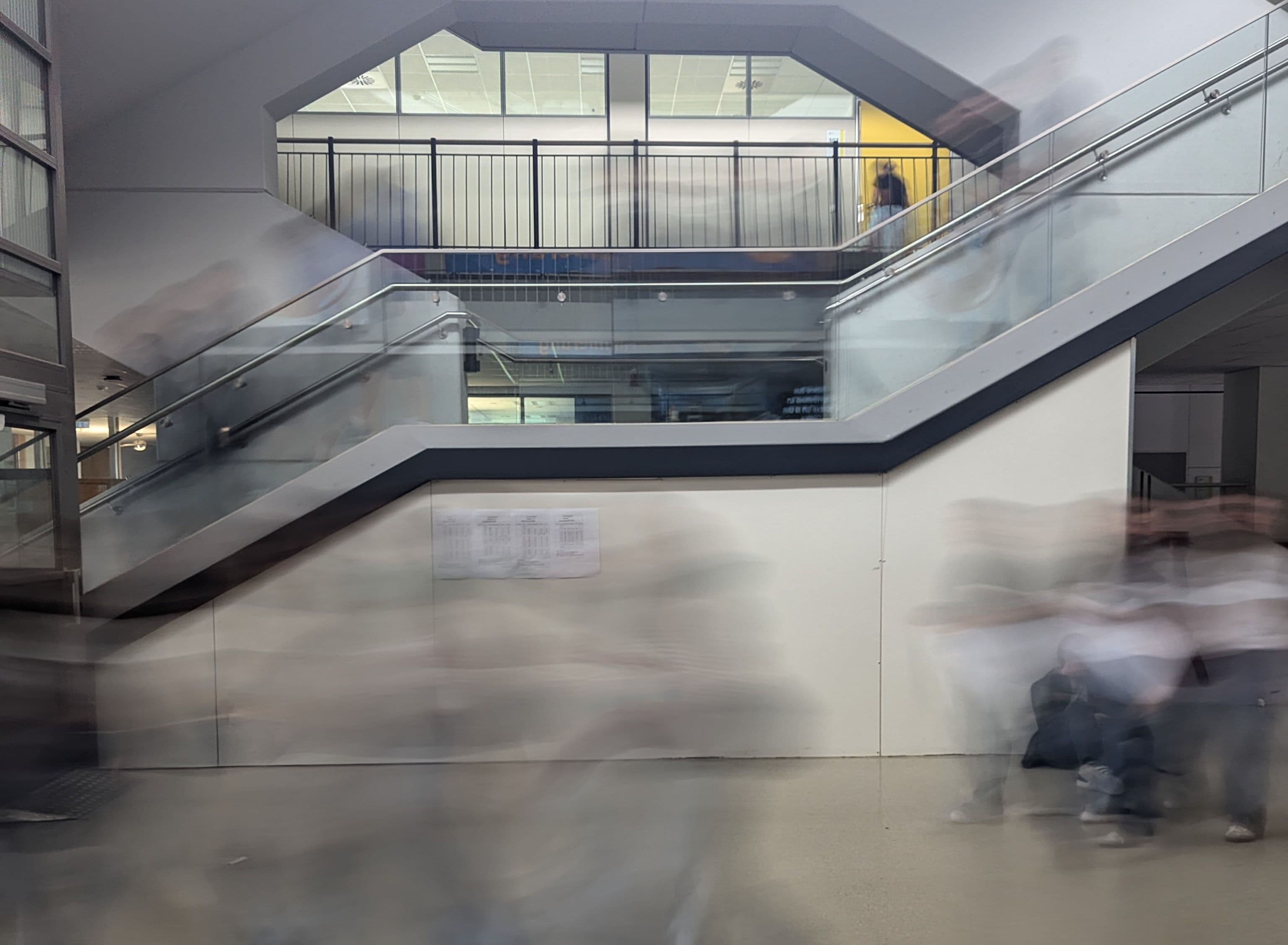 a blurry picture of people walking down stairs in a building .