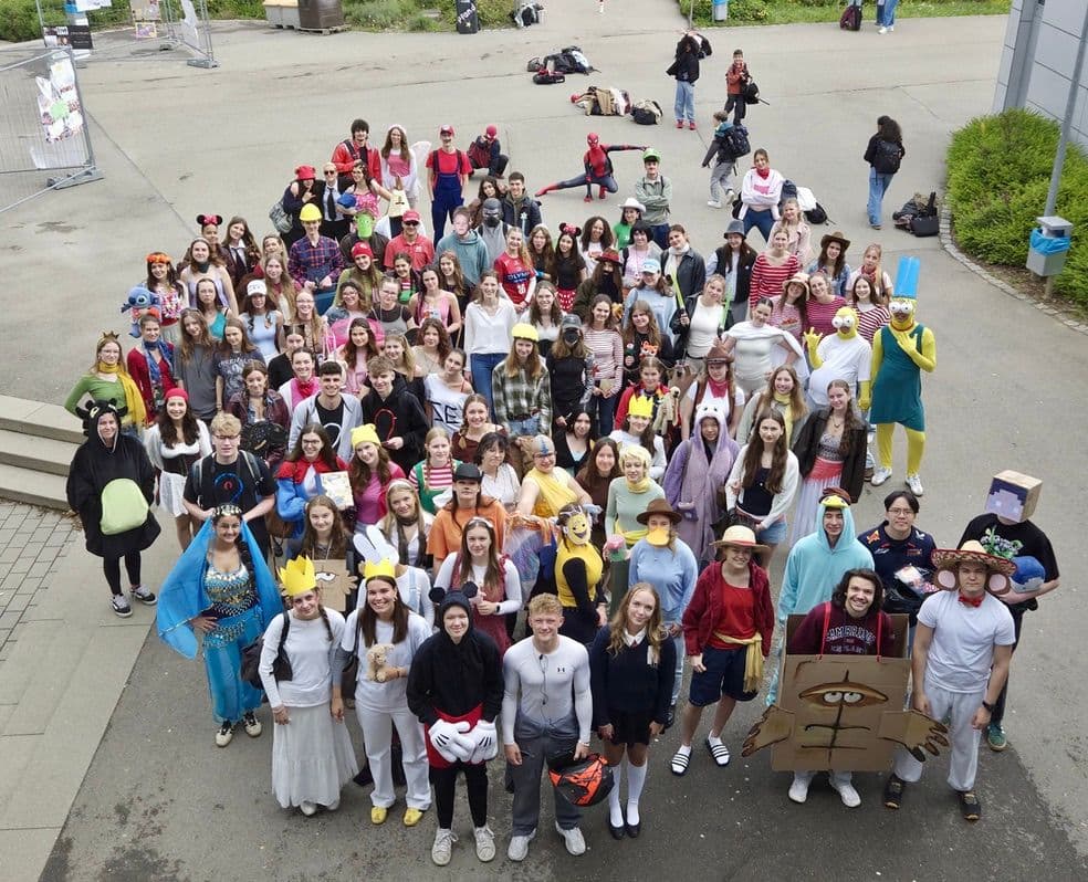 A large group of people dressed in diverse costumes posing outdoors.