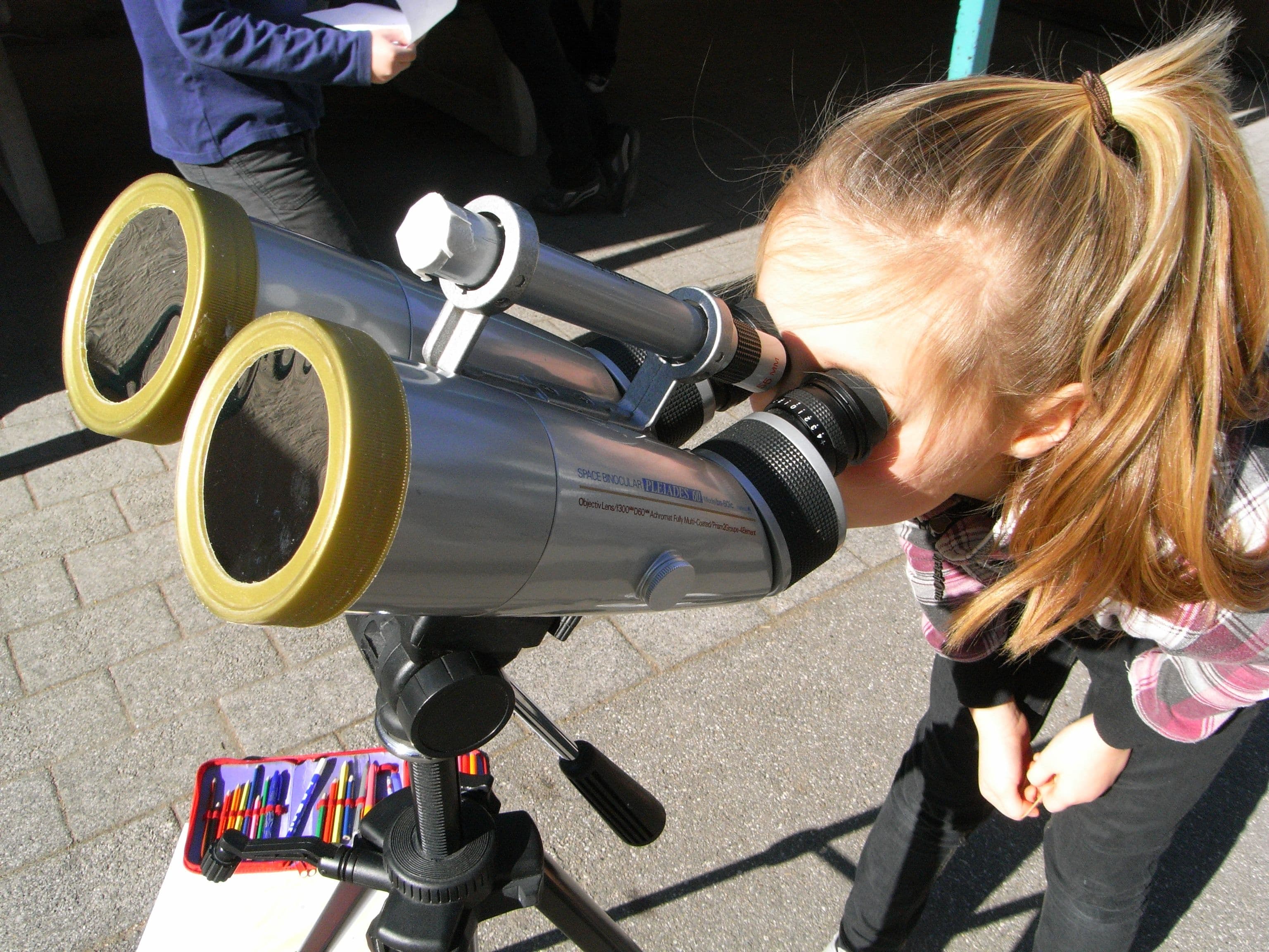 a young girl is looking through a telescope on a tripod .