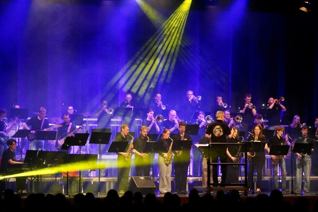 a large orchestra is playing on a stage in front of a crowd .