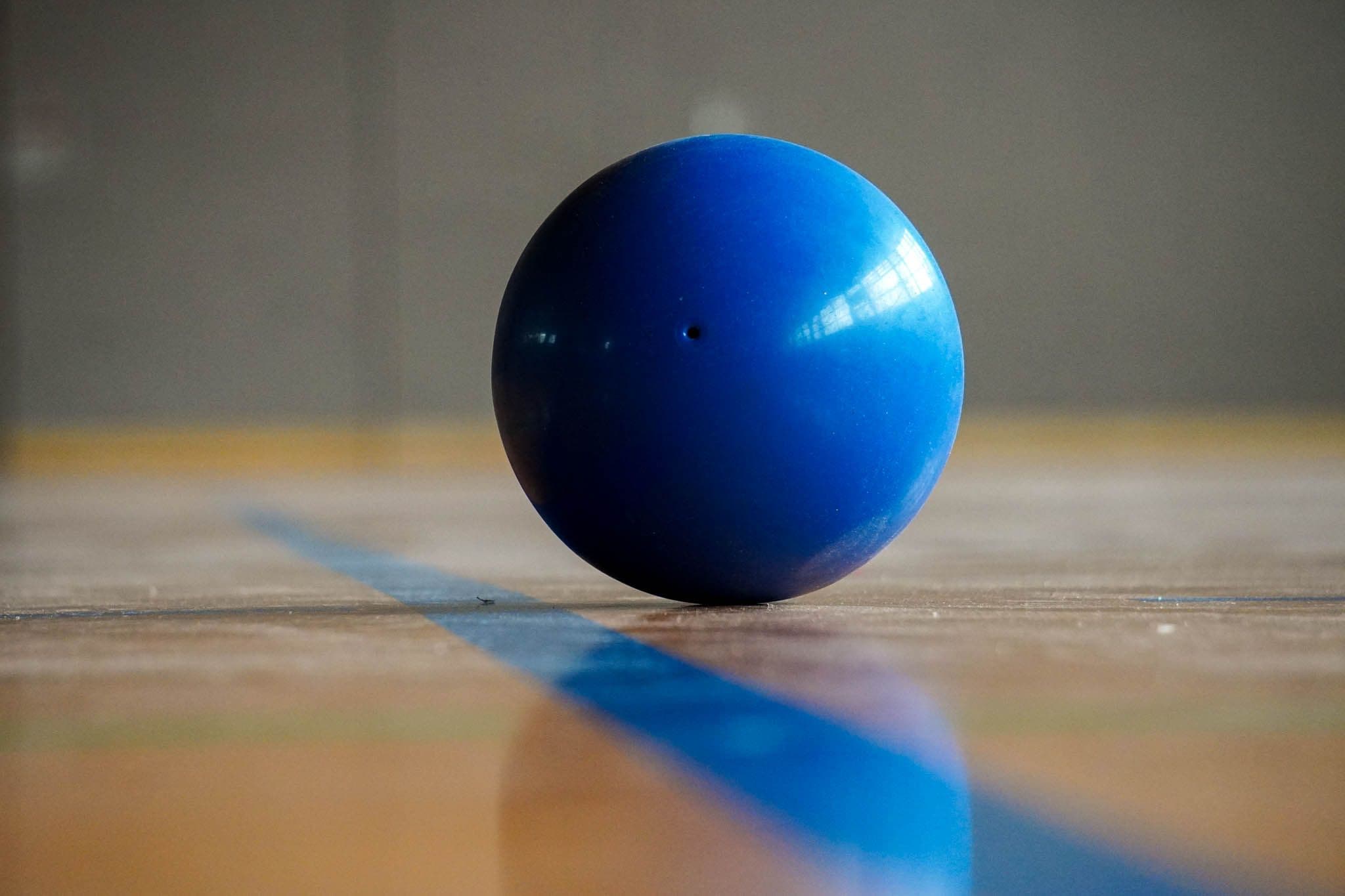Gymnastikball auf einer blauen Linie in einer Sporthalle.