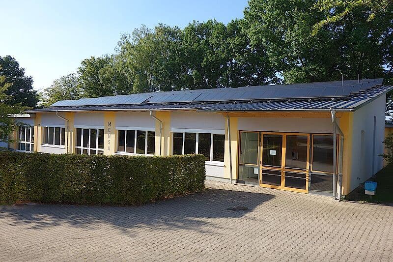 a large building (Mensa) with a lot of windows and solar panels on the roof .